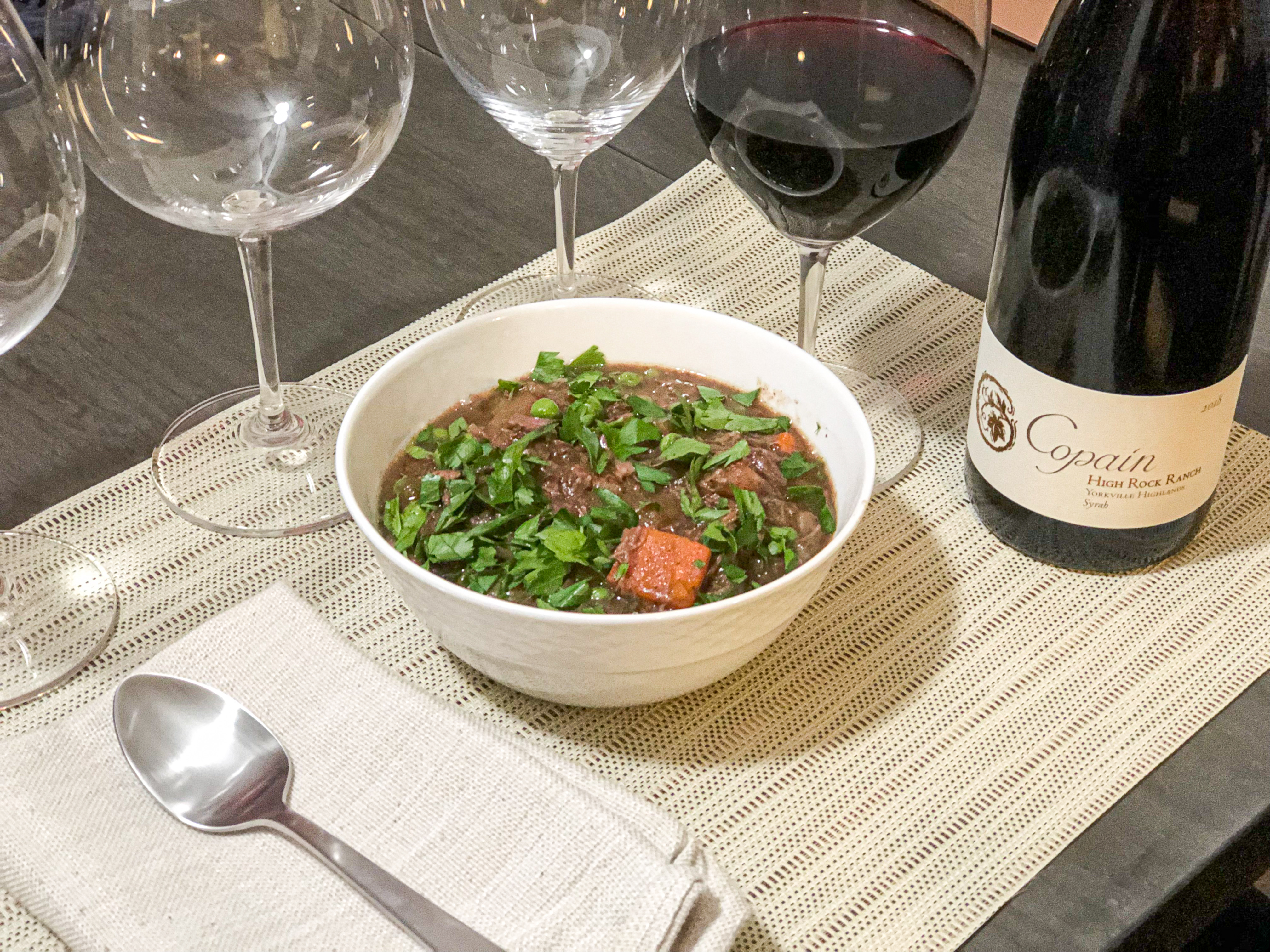 A place setting of a bowl of Boeuf Bourguignon.